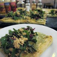gluten free vegan pizza. The crust is made of tapioca, cornmeal and rice. The topping consists of avocado cheese, sesame seeds, beetroot leaves, cashew parmesan, and olive oil.  at Las Gringas in Arequipa
