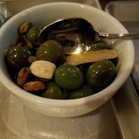 Warm Olives with rosemary, roasted garlic, pistachios and lemon infused olive oil. Delicious! at Donna Jean in San Diego