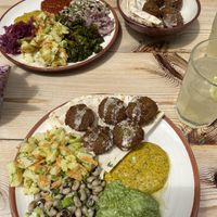 Falafel plates with assorted toppings - potato salad, black eyed beans, kale, pickled onions, red onions, harissa sauce, mustard, spinach pesto  at The Chickpea in Crete