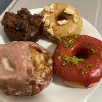 Clockwise from lower left: Pear caramel fritter, brownie pecan pie, golden milk and cookies, cranberry lime sugar at Doe Donuts in Portland