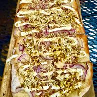 Pistachio & Red Onion Flatbread ($12), topped with olive-oil, roasted red onions, vegan parmesan, garlic-lemon dressing, and crushed pistachios. at Mahalo in Panama City