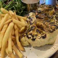 The Cajun cauliflower steak with satay sauce, rocket salad, and fries.  at Bitter & Twisted in Chipping Norton