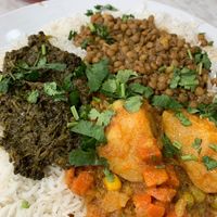 Green plate with three types of curries  at Little Aladdin in Manchester