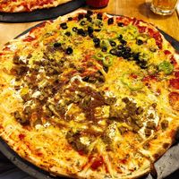 Pizza vegana, media tomate, queso vegano, seitán casero, cebolla caramelizada y mostaza; mitad de tomate, queso vegano, falafel, pimiento verde, salsa de curry y aceitunas negras at Pizzeria Trozo in Bilbao