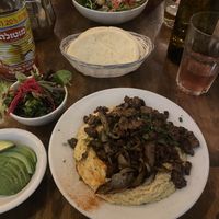The chicksteak hummus plate with a side of avocado. Across is the cauliflower of life Salad  at Chickpea Restaurant in Vancouver