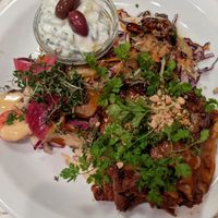 Lasagna made with nutitional yeast, nuts, lentils.  Sides are slaw with ginger vinaigrette, cucumber salad, and a tomato and onion salad at Atlas Bar in Copenhagen