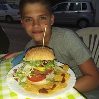 My son and the gigantic burger with salad and Nachos at Veggie Momi in Albufeira