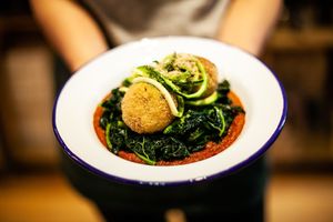 Arancini with mockzarella, courgette spaghetti, chilli marinara and sauteed greens at Infinity Foods Kitchen in Brighton