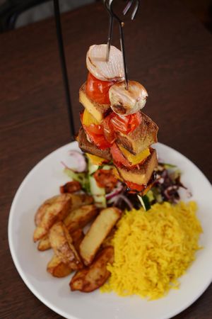 Tofu Hanging Kebabs! Devons Dragonfly Farm marinated Tofu kebabs served skewered with cherry tomatoes, peppers, onions above rice, homemade wedges & salad garnish at Rock Garden in Torquay