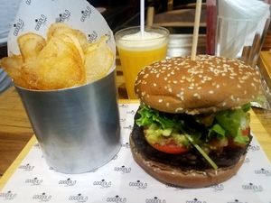 Black bean burger with guacamole, tomato, onions and greens, fresh homemade potato chips and an orange/passionfruit juice. Yum!! at Goodala Burger in Natal