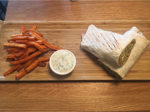 Vegan guacamole wrap with sweet fries on a bamboo board at D-Werk in Innsbruck