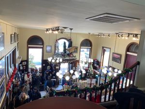 Crowded downstairs covered in Christmas decorations, taken from upstairs  at The Met Coffee House and Art Gallery in North Conway