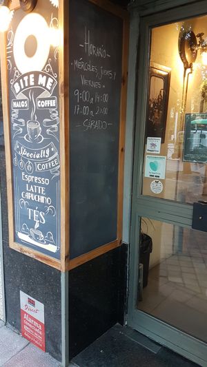 Schedule and storefront at Bite Me Cafe in Madrid