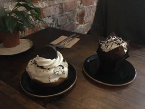 Muffin de chocolate sin gluten y halo “Golden Oreo”, relleno de crema de vainilla y galleta golden, glaseado de chocolate blanco, polvo de galleta oreo y nata [producto tempora at Bite Me Cafe in Madrid