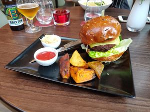 The Wulf Burger [£14.95] - Seitan patty, tomato, baby gem, pickle, red onion, cashew aioli in a brioche bun with sauerkraut, sweet potato and potato wedges.  at Wulf & Lamb Chelsea in London