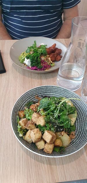 Green bowl in the front, cauliflower fritters in the back at SoulPod Foods in Croydon