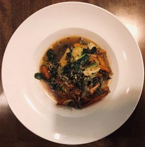 Agnolotti en brodo: sweet potato agnolotti, foraged mushrooms, shaved brussels, spinach, roast carrot, roasted garlic-chaga broth at Twisted Fern in Park City