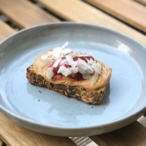Our toasted in-house Ultra Seedy Bread with Almond Butter, Strawberry Conserve and Coconut Flakes. at mymuybueno Deli in Mallorca