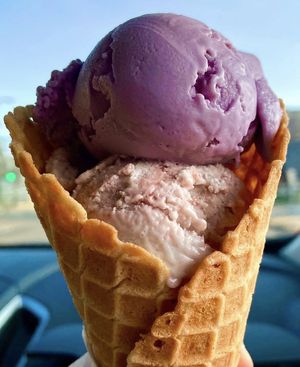 Two scoops in a waffle cone: strawberry cheesecake and ube flavor 💕  at Crepe and Spoon in Minneapolis