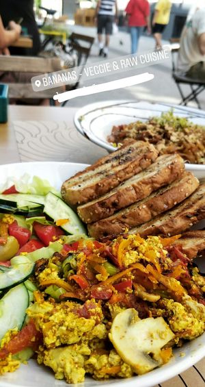 Vegan "omelette" which was closer  to a scrambled tofu, amazing seasoning. Toasted bread with oil and herbs and a salad. On the background is the vegan Pad Thai. at Bananas Veggie & Raw Cuisine in Novi Sad