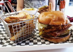 Double bacon cheeseburger (two tempeh mushroom patties, cheese sauce, BBQ sauce, soy bacon strips, mayo, pickles, and lettuce on a brioche bun), served with potato wedges. at Mythology in Toronto