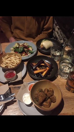 Eggplant steak w/ cauliflower (grey plate) - tofu bao bun (black plate) - fries (brown bowl) - roasted carrots (black bowl) - jackfruit chicken nuggets (brown bowl) at Yonder in Queenstown