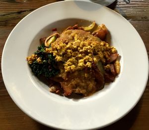 Tempeh bacon hash: Potatoes and caramelized onions, seasonal vegetables, tempeh bacon and kale, seasoned with herbs and smoked paprika. topped with green chile and tofu at City O' City in Denver