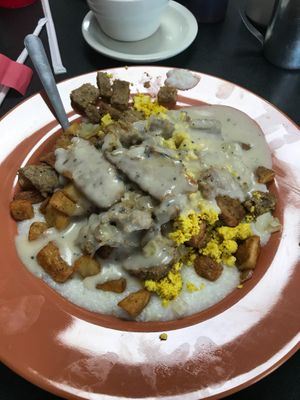 Vegan Smothered Stuffer- Grits, spuds, grilled onions, cheeze, vegan egg, faken bacon, vegan breakfast sausage, and vegan egg covered in vegan peppered gravy at Ocala's Downtown Diner in Ocala
