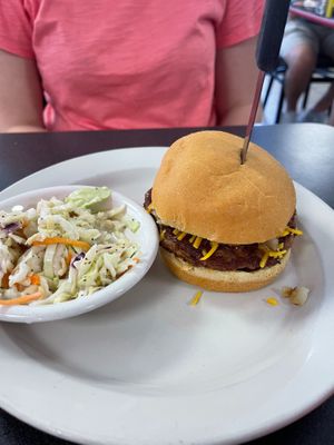 Vegan BBQ Burger with Beyond patty and a side of vegan cole slaw.  Burger topped with grilled onions, BBQ sauce, vegan cheeze, and vegan mayo at Ocala's Downtown Diner in Ocala