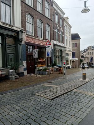 Outside seating area, window with cakes and entrance at Bairro Alto in Nijmegen