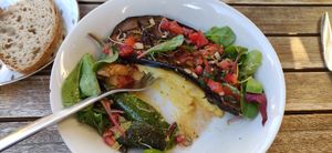 Creamy polenta with roasted eggplant, tomato and dark olives sauce, chiogga beet, and pomegranate seeds. at SOJI in Marseille