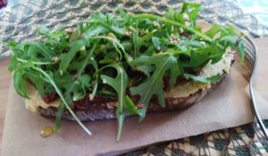 Delicious Tartine with hummus, dry tomatoes, a pile of  rocket, and olive oil! simple, and efficient at Dona Flor Cafe in Lisbon