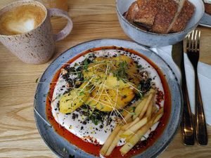 Cafe latte and amazing breakfast: plant-based labneh, roasted potatoes, black lentils, russet apple and chili oil. at Zaczyn in Krakow