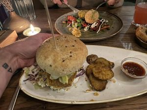 Tempeh Burger with sliced baked potato 28.00.- (smoked tempeh burger with tartar sauce, red cabbage, lettuce, pickled onions, and spicy oven baked potato slices)  at Karls Kraut in Luzern