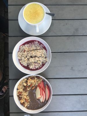 turmeric latte, overnight oats (plum preserves), and acai bowl with apples at My Goodness in Berlin