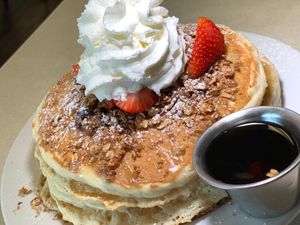 Vegan Almond Layer Cake: Pancakes, Vanilla Cream Filling, Blueberries, Strawberries, Granola, Vanilla Glaze, Coconut Whipped Cream, Syrup at Noble Restaurant in Wyoming
