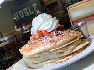 Vegan Almond Layer Cake: Pancakes, Vanilla Cream Filling, Blueberries, Strawberries, Granola, Vanilla Glaze, Coconut Whipped Cream, Syrup at Noble Restaurant in Wyoming