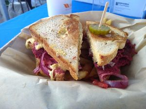 Seitan Ruben sandwich atop fries. at Original Herbivore - Food Truck in Los Angeles