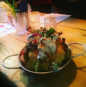 Whole roasted cauliflower with tomato cherry and tahiny sauce. Vegan at Shouk in Drumcondra