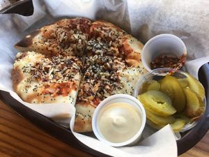 Onion flatbread served with tahini sauce, pickles, & chili sauce.  at Frena Bakery and Café - Soma in San Francisco