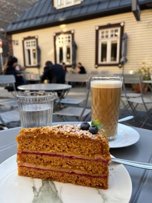 “No-honey” cake, a cafe latte, and outdoor seating. at Mazā Terapija in Riga
