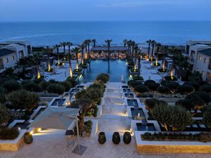 The restaurant is visible at the far end of the swimming pool. Outdoor seating. Gorgeous atmosphere with view of sea. at Azur - Four Seasons Hotel in Tunis