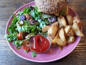 Mexican burger: seeded bun with a lentil/mushroom patty, vegan mayo, tomato sauce, vegan cheese, pickled red onions, avocado, tomato, lettuce and Jalapenos. Served with a side salad and potatoes (6.90 euros) at RoseHip Vegan Kebabs in Vilnius