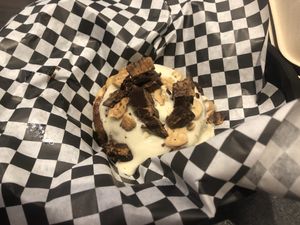 A bun with cake batter frosting, peanut butter cups and animal cookies   at Cinnaholic in Boca Raton