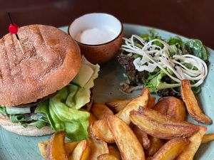 Portobello Burger
Burger van portobello op een brioche met amandel-ricoa, rode uichutney, amandelschaafsel, ketchup, sla, komkommerlinten, ingemaakte
kool, ovenfriet en aioli.  at Bhalu in Nijmegen