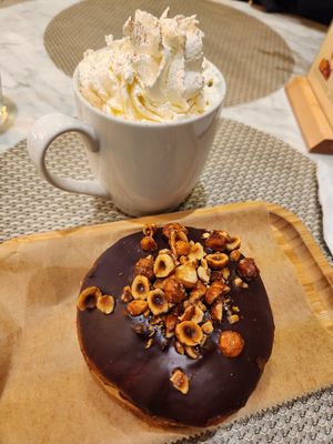 Whipped cream (best ever) on oatmilk latte, with Rocher donut (caramelized hazelnuts and hazelnut pastry cream inside) at L'Artisane Creative Bakery in Coral Gables