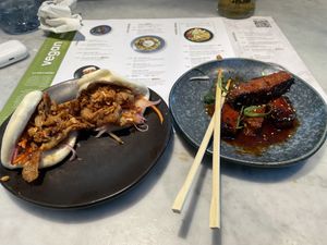 Spicy teriyaki vegan ‘chicken’ hursts steamed buns and partially devoured sticky vegan ‘ribs'  at LHR - Wagamama - T5 in West London