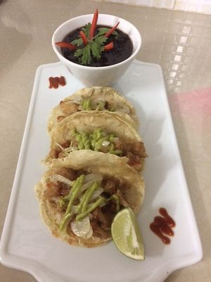 BBQ Beer Braised Cauliflower tacos with grilled onions and topped with avocado cream. Served with a side of Black Beans at Iguana Juan's in San Pedro