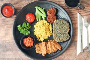 Full English Breakfast with vegan sausage, beans in bbq sauce, pesto toast, sweet potato hash browns, scrambled tofu, roast tomato and crunchy sugar snaps at Nourish Cafe in Bangkok