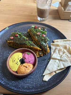 Weinblätter gerollter Duftreis mit Dill, Petersilie und Berberitzen, fein gewürzt mit Kurkuma & Zimt, sanft geschmort., Dazu Safran-Joghurt und Granatapfel (vegan) 12,90€  at Schadzi Cafe in Linz